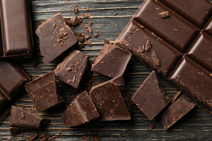 Chocolate pieces on wooden background, close up