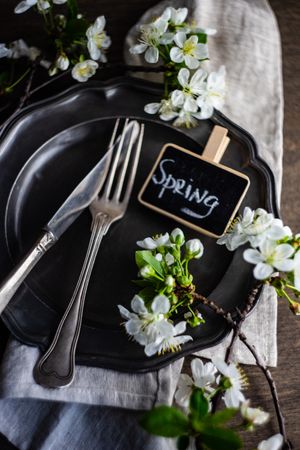 Spring table setting with blossoms on a dark plate