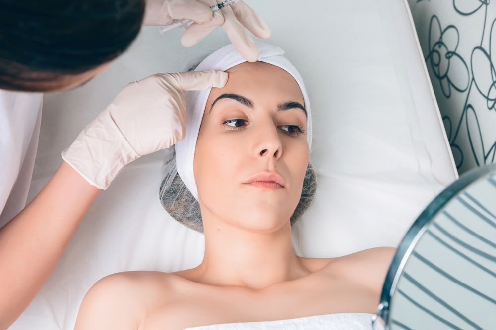 Female checking forehead in mirror after botox in a beauty salon