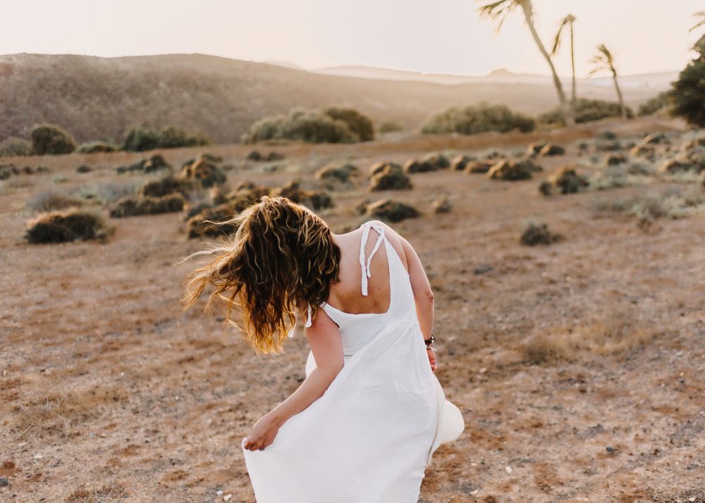 Woman in white dress in dry field in sunlight