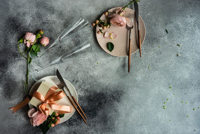 Pink flowers and gift on plates with grey background