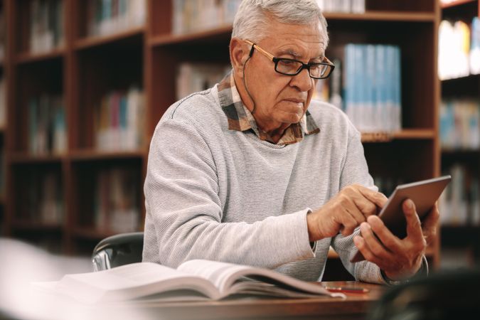 Older male working on tablet in college library