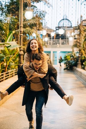 Man carrying happy girlfriend on back