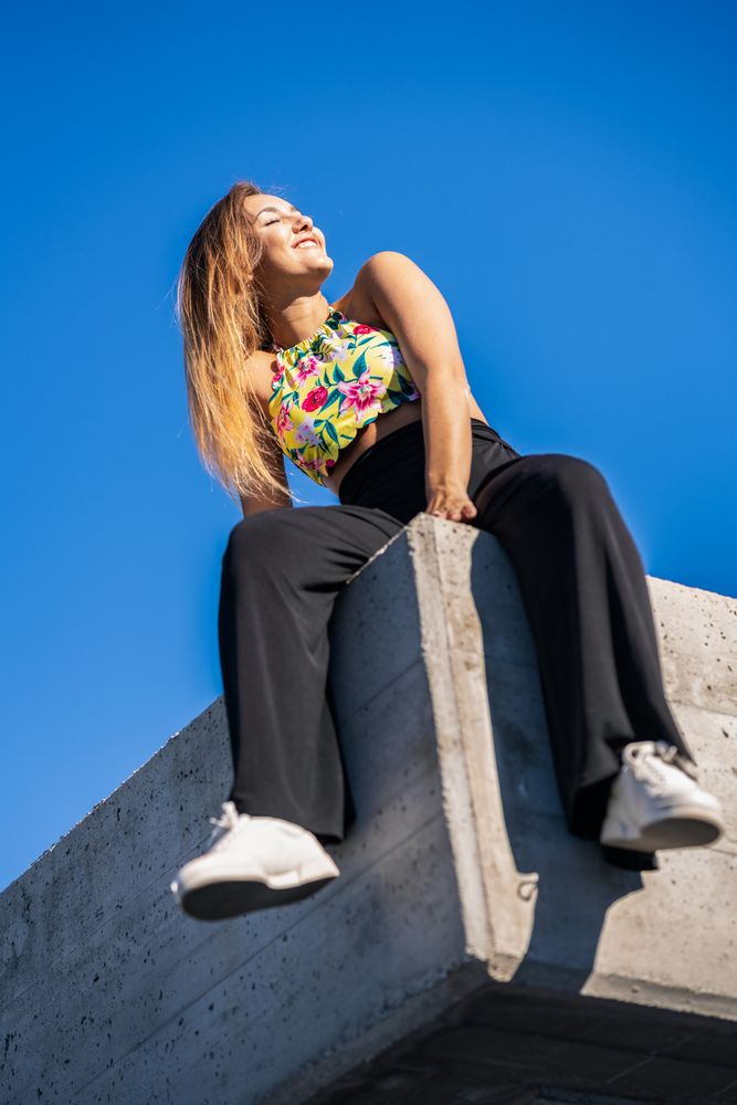 Happy woman sitting on corner of building roof with eyes closed