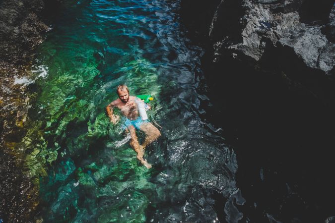Man swimming in water with rubbish