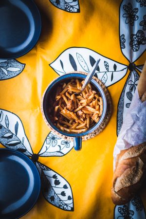 Mug with pasta near bread and bowls