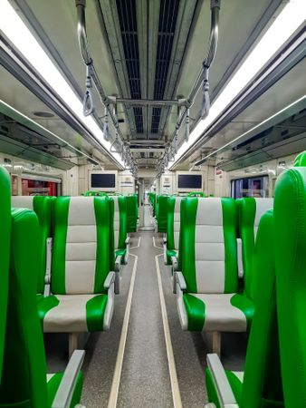 Modern train interior with comfortable seats and green color.