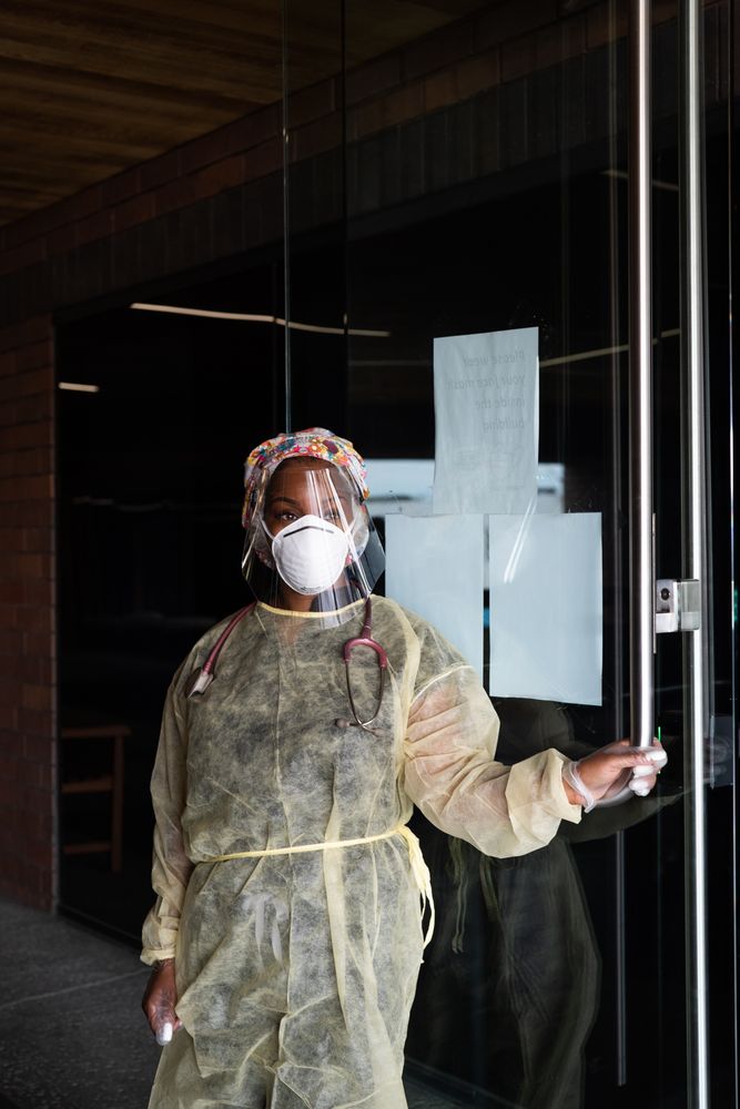 Three-quarter length shot of female nurse standing on doorway of medical building