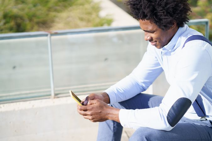 Side view of a man holding a yellow phone