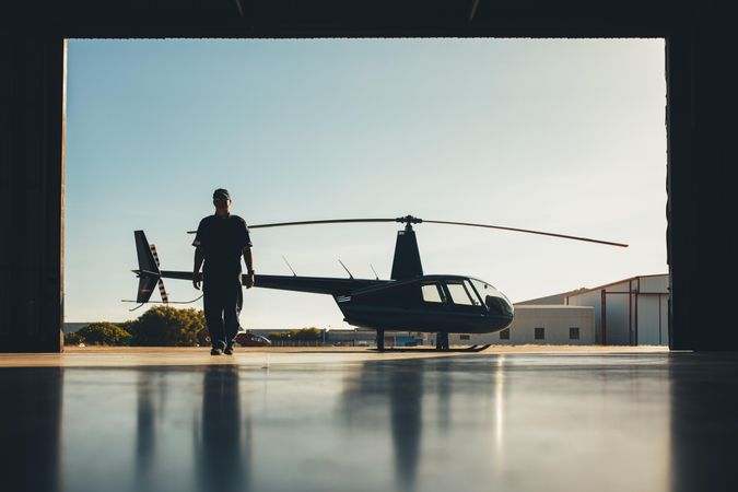 Silhouette of helicopter with a pilot in the airplane hangar