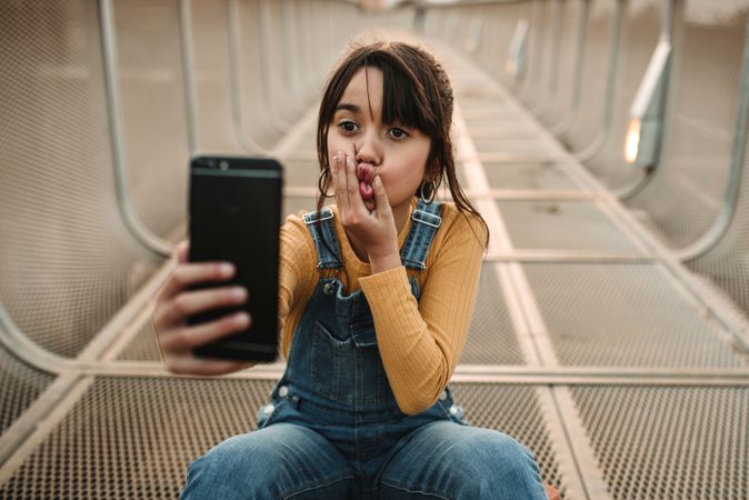 Funny girl taking selfie on smartphone on walkway