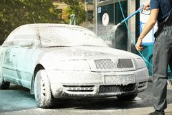 A man washes a car in a manual car wash. Clear car