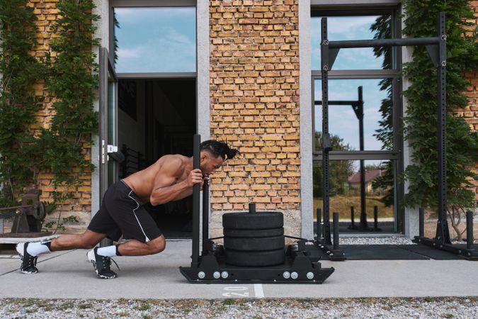 Black guy pulling weights in outdoor gym