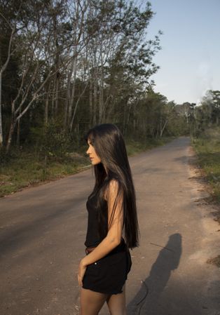 Side view of woman in dark shirt and short standing on road