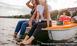 Cropped shot of two women friends sitting on front of boat in city river 4m67Nb