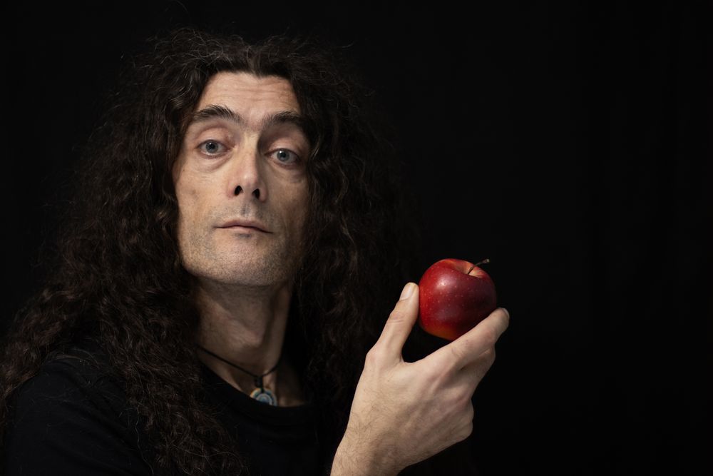 Portrait of a Man Holding a Red Apple in Shadow.