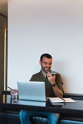 Positive man recording audio message near laptop