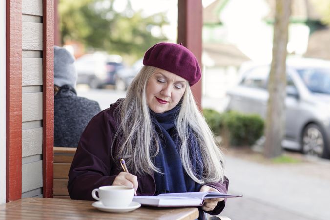Woman reflecting her thoughts into a notebook at a coffee shop