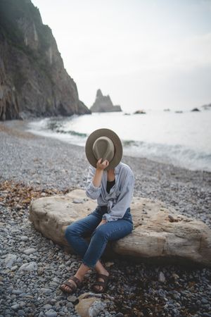 Woman resting on beach stone by sea