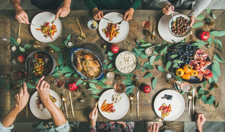 Group eating at festive table with roasted chicken, pomegranates