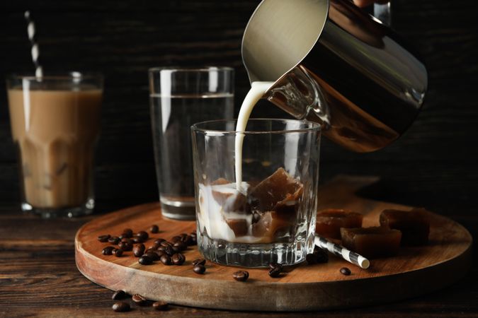 Milk is poured into a glass of coffee. Composition with ice coffee