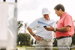 Two golf players standing together using mobile phone 5XlEM5