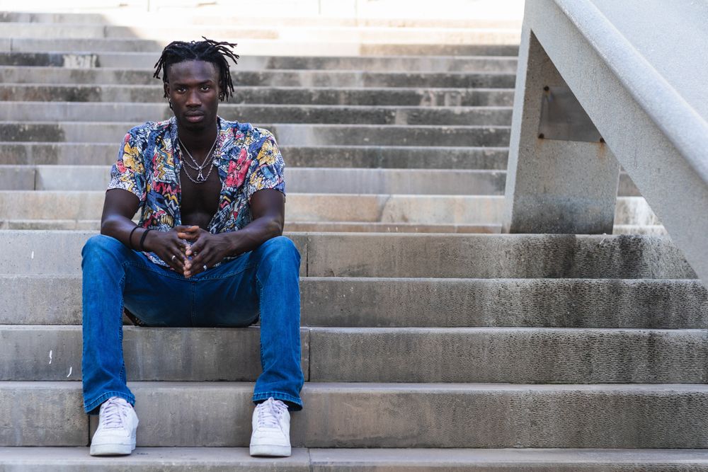 Stylish Black hipster man sitting on stairs in city