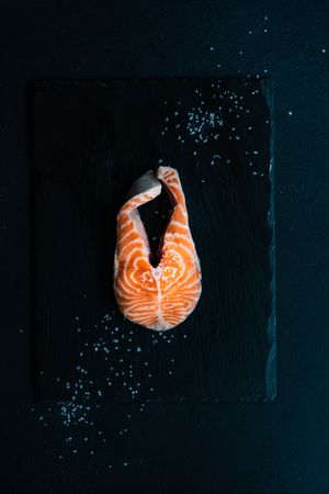 Top view of salmon steak on dark counter with copy space, vertical composition