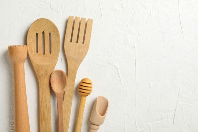 Wooden kitchen cutlery on plain background, space for text