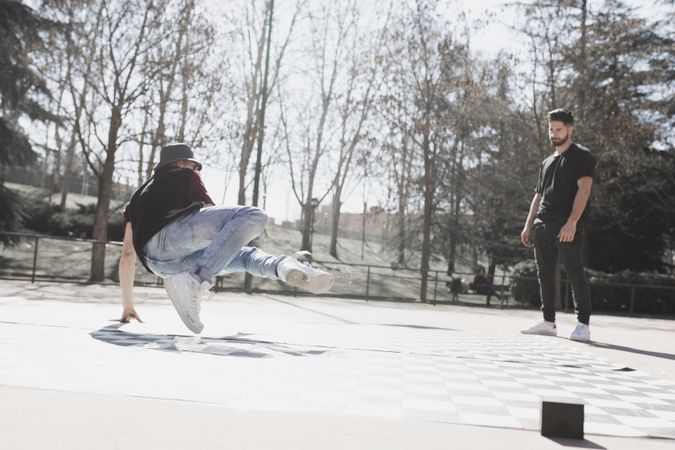 Guy looking at man dancing break dance in park