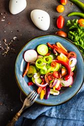 Top view of delicious healthy raw vegetable salad served on blue plate