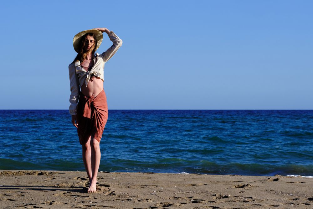 A fashion model with a hat at the beach before sunset