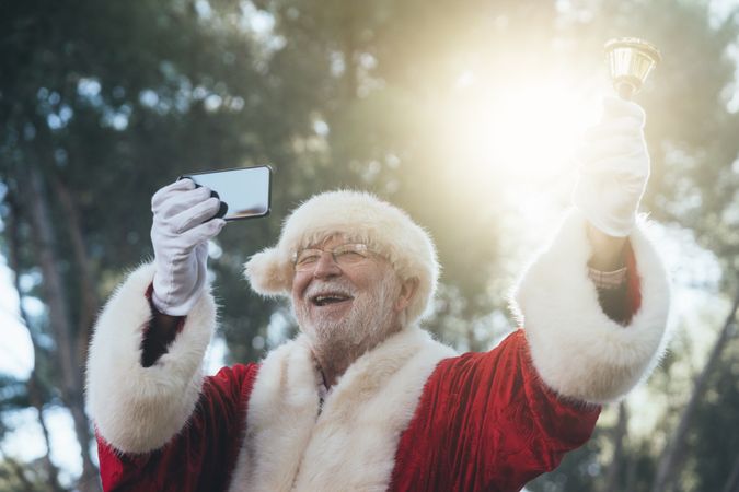 Happy Santa Claus with smartphone and bell