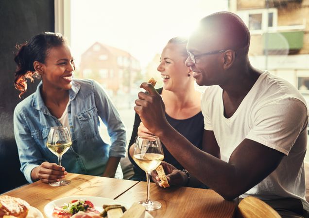 Multi-ethnic group smiling in a restaurant with wine and snacks