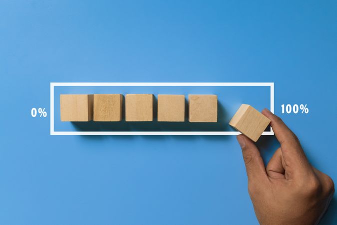 male hand put wooden blocks in loading screen isolated on blue background. progress concept