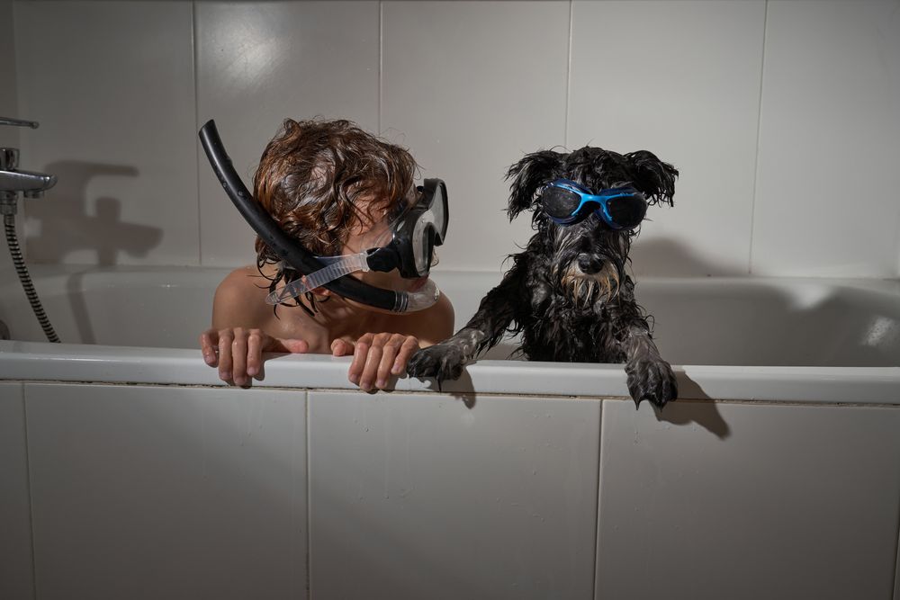 Boy in diving mask with dog in bathtub
