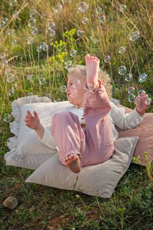 Adorable little girl lying on pillow on grassy meadow