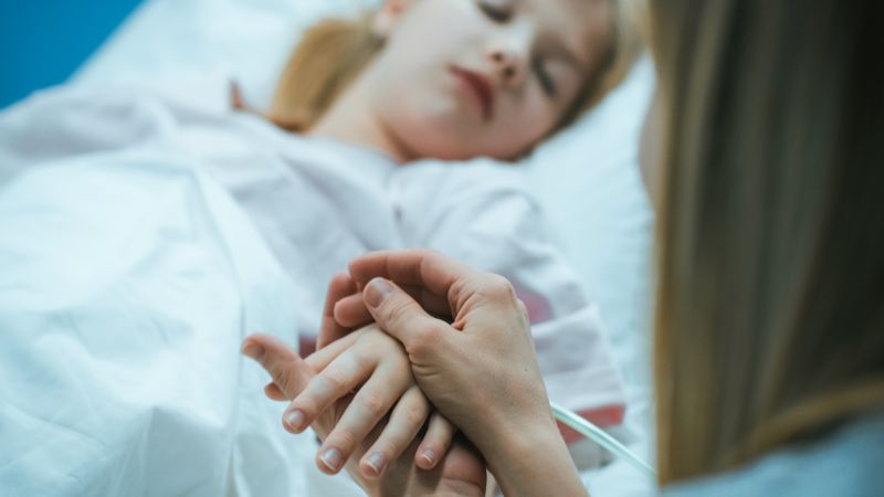 Mother Takes and Holds Hand of Her Sick Little Girl who Is Sleeping in the Hospital Bed.