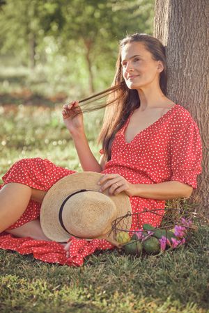 Young woman with hat sitting on grass