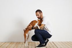 Man crouching down as dog tries to get onto his lap