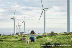 Cheerful woman running on green grass nearby wind turbine farm in Lanzarote, Spain 5lKj70