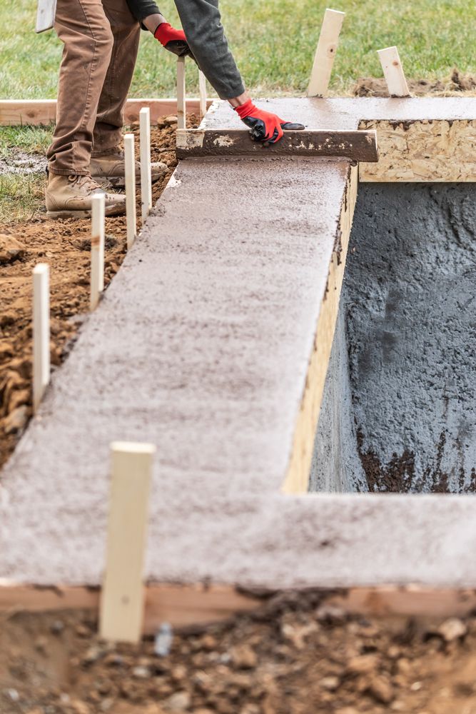 Construction Worker Leveling Wet Cement Into Wood Framing