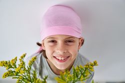 Cheerful child in pink bandana with goldenrods