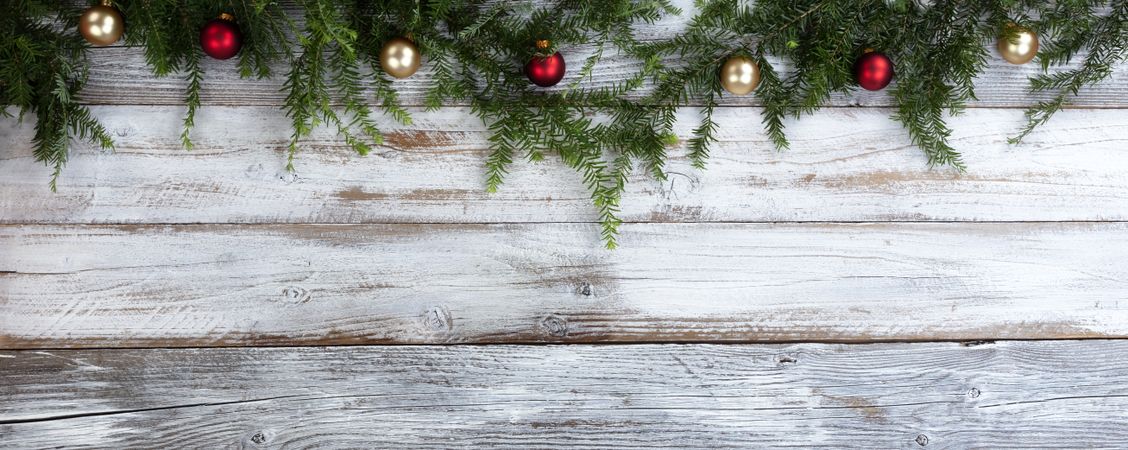 Real fir branches with gold and red ball ornaments on rustic wood for the Christmas or New Year holiday background