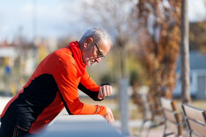 Male leaning over cement wall checking watch