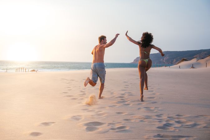 Happy couple running on tropical romantic beach