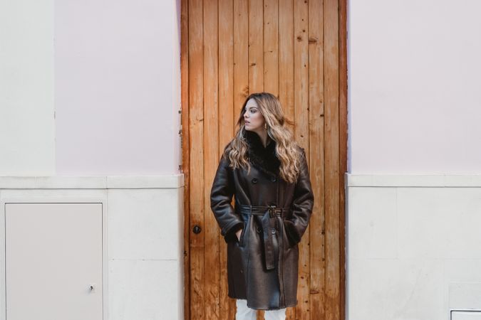 Stylish woman standing near brown door