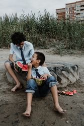 Little boys playing while eating watermelon on beach