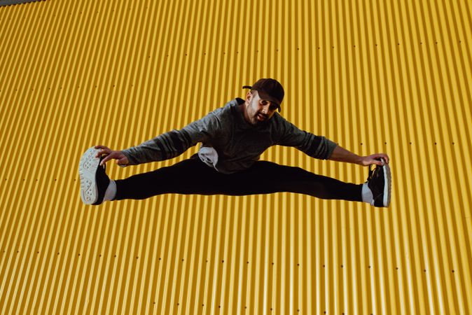 Man jumping near yellow wall