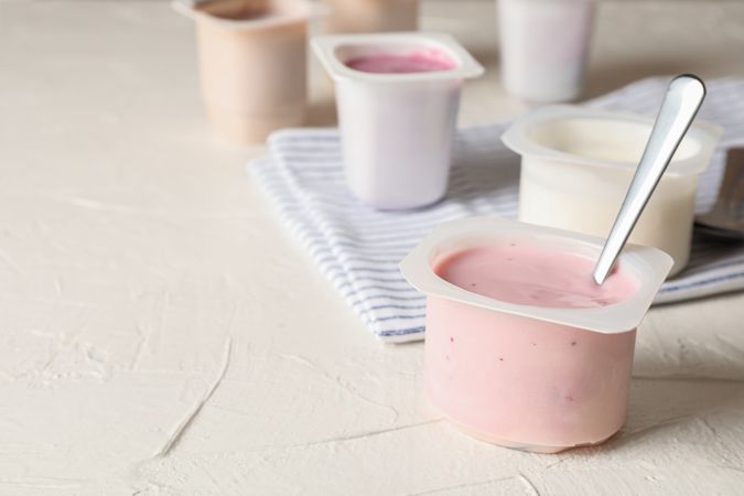 Composition with plastic cups with yogurt on table